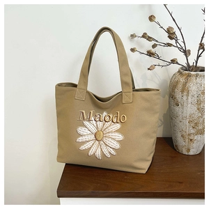Gros plan détaillé du sac cabas en toile kaki avec broderie marguerite et lettrage Maodo