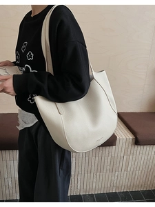 Close-up of cream white crescent tote bag with lychee texture and minimalist logo detail