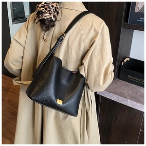 Détail du sac hobo en cuir noir grainé avec logo en métal doré et bandoulière réglable