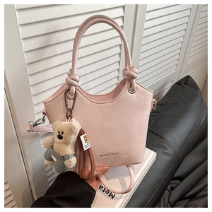Detail view of pink bucket bag featuring a knot handle and cute teddy bear charm