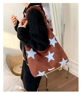 Detail of dark brown suede shoulder bag featuring soft blue plush star patterns