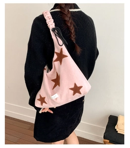 Detail of pink shoulder bag with brown star pattern and ruffled strap on a model