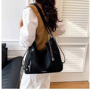 Detail of black leather tote bag with silver zipper tassel and hanging mini pouch
