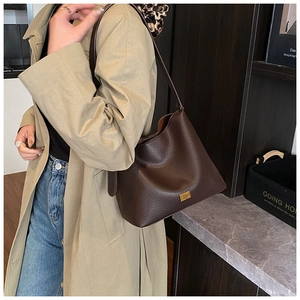 Texture détaillée du sac à bandoulière en cuir grainé marron avec plaque dorée