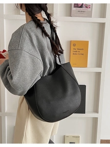 Detail of black pebbled leather tote bag with embossed logo on a lifestyle background