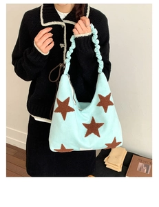 Detail of light blue plush tote bag with brown star pattern and ruched handle design