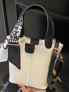 Chic beige bucket bag with black top handle and decorative silk scarf for women