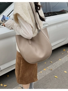 Outdoor shot of a beige leather tote bag with pebble texture and curved silhouette