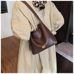Détail du cabas en cuir grainé marron foncé avec élégante plaque de logo dorée