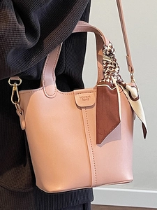 Pale pink bucket bag with printed silk scarf handle and adjustable crossbody strap