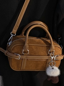 Caramel brown vintage suede crossbody bag with dual handles and stylish fluffy ball charm