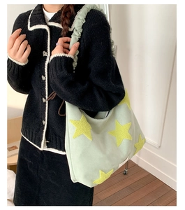 Detail of light green canvas tote bag with yellow star embroidery on shoulder strap