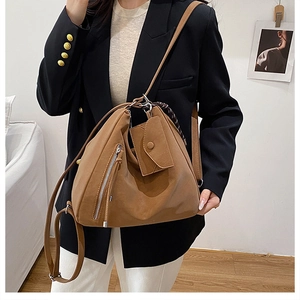Detail of a brown matte leather tote bag featuring a decorative silk scarf and side zippers