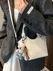 White leather bucket bag with bear pendant and crossbody strap for elegant women