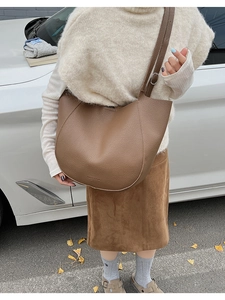Detail of a brown lychee-grain leather tote bag showing texture and adjustable strap