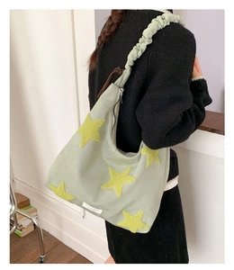 Close-up of mint green tote bag with yellow star patches and ruched shoulder strap details