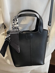 Fashionable black bucket bag with patterned scarf handle and detachable gold-tone strap