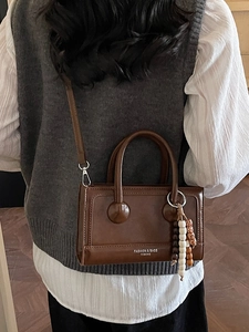 Brown vintage PU leather handbag with beaded pendant shown in a stylish back view
