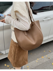 Brown leather tote bag with lychee texture shown in a casual outdoor shoulder carry view