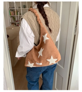Brown fuzzy tote bag with white stars and pleated strap shown on a model's shoulder