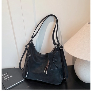 Close-up of black tote bag with silver hardware and a small envelope charm attached