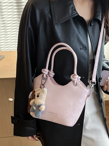Pink minimalist bucket bag with knotted handle and cute bear charm shown on model