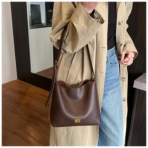Détail du sac cabas en cuir marron avec logo doré et bandoulière réglable élégante