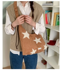 Close-up of brown suede shoulder bag featuring white plush star patches and drawstring