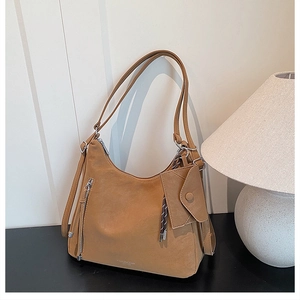 Detail of camel tote bag with side zipper and matching mini pouch on a black table