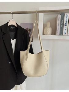 Detail of beige lychee leather tote bag with adjustable strap on a minimalist hanger