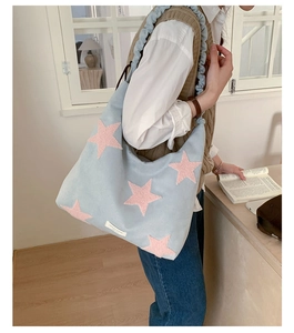 Detailed view of canvas tote bag with pink plush stars and ruffled shoulder strap