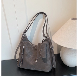 Detail of dark grey leather tote bag with small pouch and brand logo on black surface