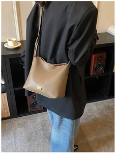 Détail du sac cabas en cuir grainé marron avec plaque métallique dorée et logo chic