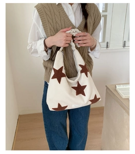 Detail of cream shoulder bag with brown plush star and scrunchie handle on model