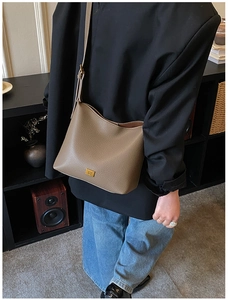 Détail du sac à bandoulière gris café en cuir grainé avec logo métallique carré