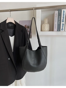 Close-up of black lychee grain leather tote bag with slim shoulder strap and minimalist style