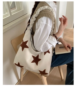 Detail of white star print tote bag featuring ruffled strap and side zipper pocket