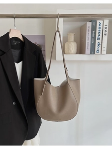 Detail of tan pebble leather tote bag hanging on a rack showing the smooth texture and strap
