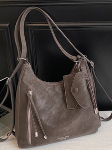 Brown faux suede tote bag with fringe charm and small pouch on a minimalist background