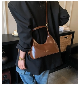 Vue détaillée du sac porté épaule marron brillant avec logo doré et finition de qualité