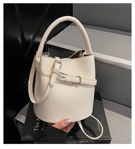 Detailed macro of minimalist off-white bucket bag with premium lychee grain texture