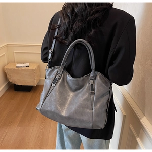 Macro view of dark grey leather handbag showing soft pleated texture and silver hardware