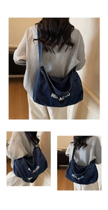 Detail of dark blue denim tote bag featuring white REPLACED text and wide shoulder strap