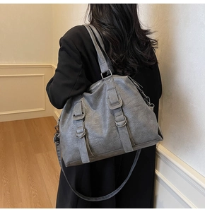 Grey large capacity leather tote bag with double strap details worn over the shoulder
