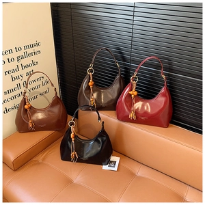 Vue détaillée des sacs hobo en cuir PU brillant avec glands en perles de bois et logo de marque