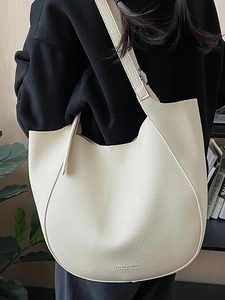Minimalist white pebbled leather tote bag with wide strap for versatile shoulder wear