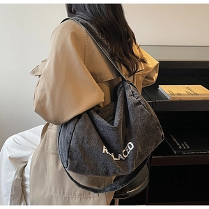 Detail view of large grey washed denim crossbody bag featuring REPLACED letter print