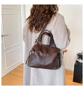 Model wearing a dark brown lychee leather handbag in a minimalist indoor setting