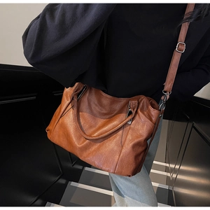 Detailed texture of brown faux leather tote bag with silver hardware and shoulder strap