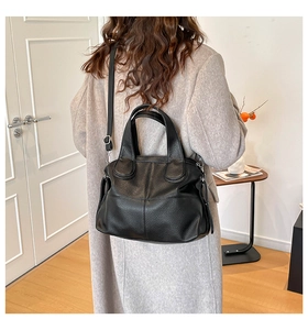 Rear view of model carrying a black pebble leather tote bag in a minimalist room